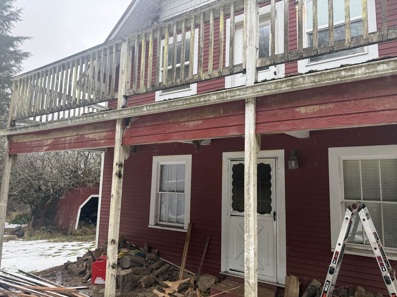Second-story deck with weathered, failing railing and rotted trim